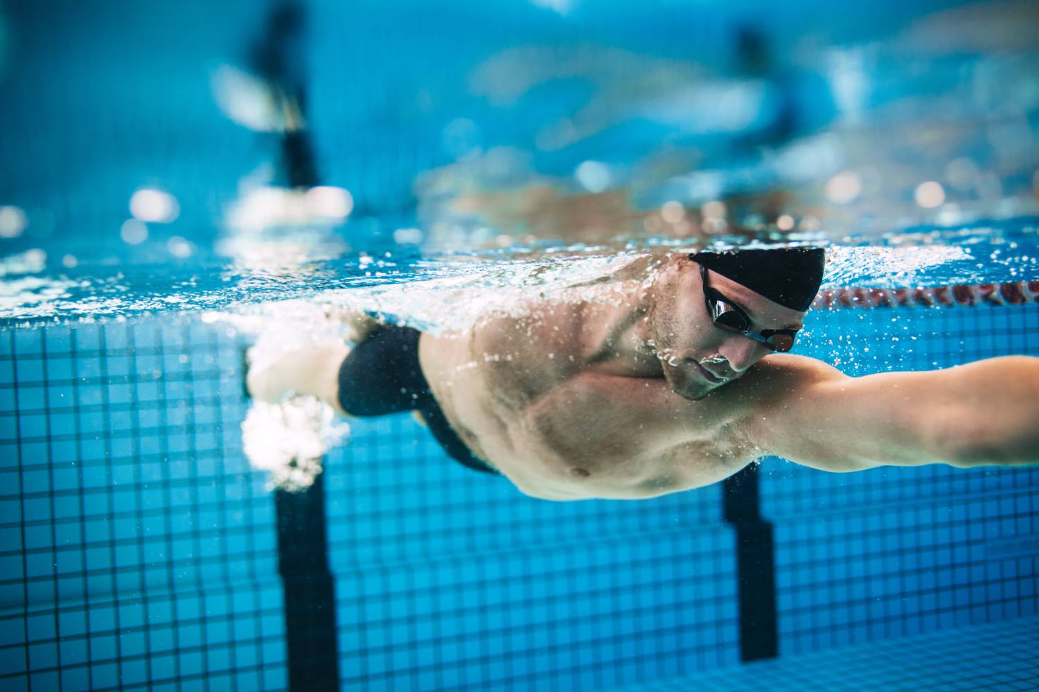 Underwater shot of professional male athlete swimming in pool. Man swimmer in action.